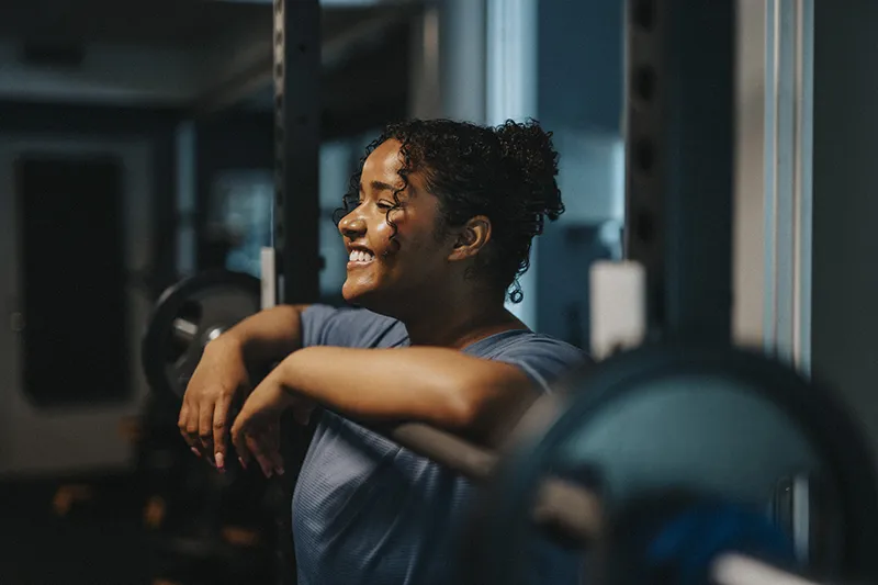 Smiling woman in a Champaign physical therapy clinic resting between rehab exercises, showcasing strength and recovery progress.